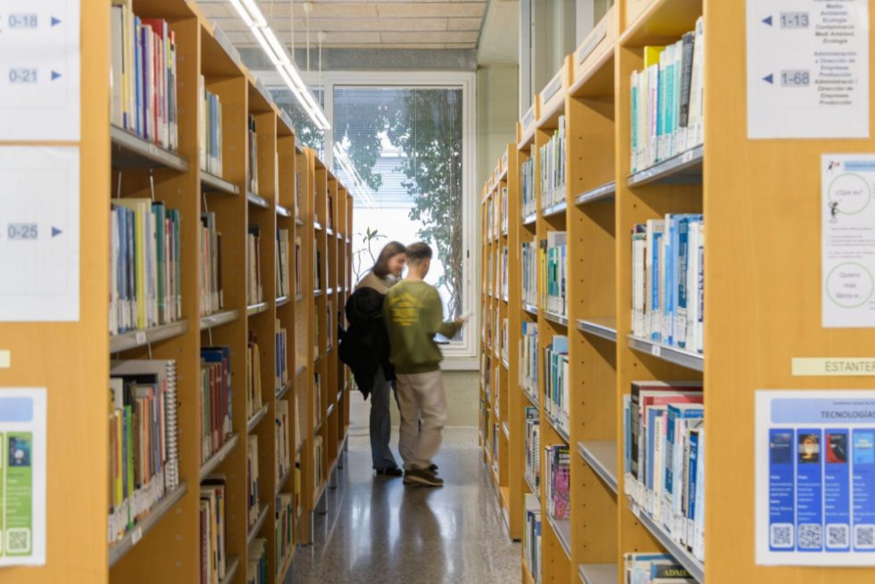 Alumnos sacando libros de las estanterías de la Biblioteca de la ETSII, Escuela de Ingeniería Industrial.